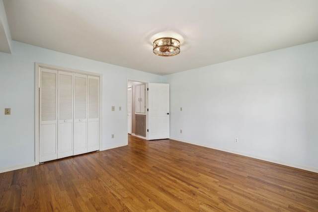 unfurnished bedroom featuring wood finished floors, a closet, and baseboards