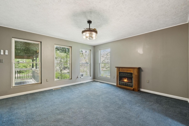 unfurnished living room with baseboards, a glass covered fireplace, a textured ceiling, and visible vents