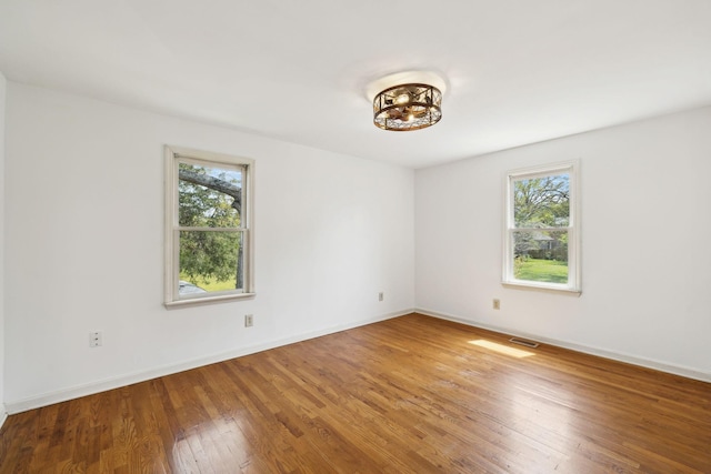 unfurnished room featuring plenty of natural light, baseboards, and wood finished floors
