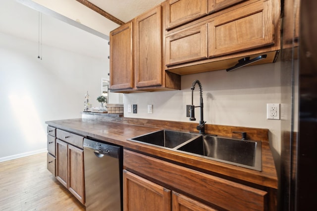 kitchen featuring stainless steel dishwasher, a sink, brown cabinets, light wood-type flooring, and baseboards