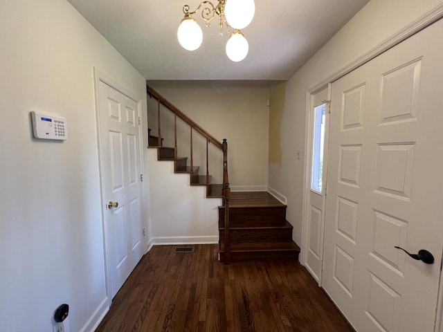 foyer with baseboards, an inviting chandelier, stairway, dark wood-style floors, and visible vents