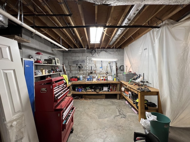 unfinished basement featuring concrete block wall and a workshop area