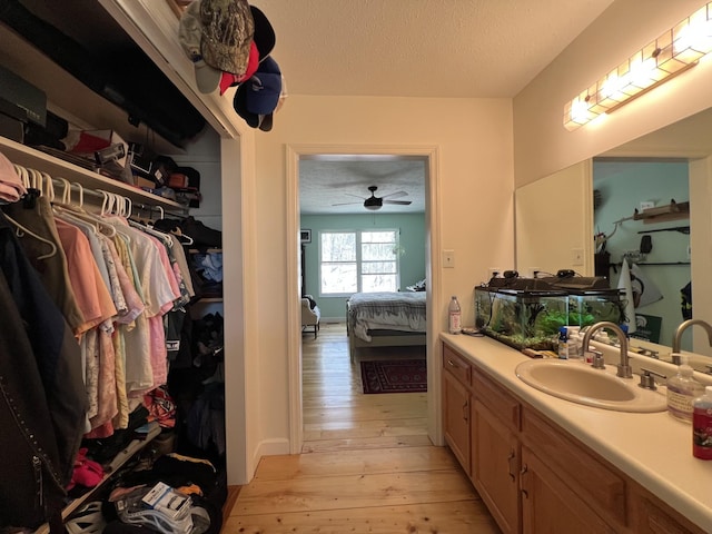 bathroom featuring a textured ceiling, a walk in closet, connected bathroom, vanity, and hardwood / wood-style floors