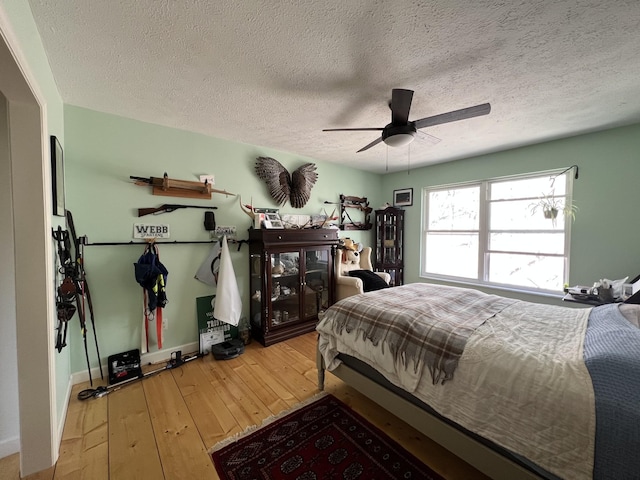 bedroom with ceiling fan, hardwood / wood-style floors, baseboards, and a textured ceiling