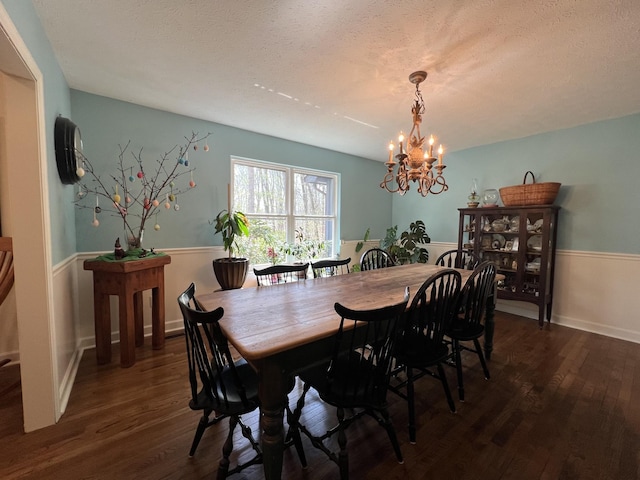 dining area featuring a notable chandelier, wood finished floors, and a textured ceiling