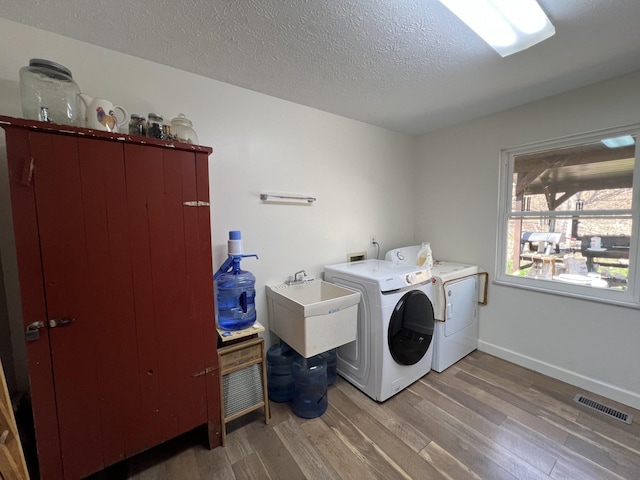 washroom with laundry area, light wood-style flooring, visible vents, baseboards, and washing machine and dryer