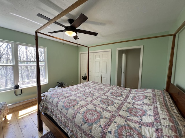 bedroom with a textured ceiling, multiple windows, and hardwood / wood-style flooring