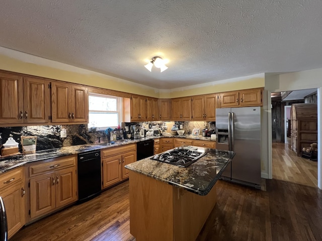kitchen with dark wood finished floors, dark stone countertops, black dishwasher, a center island, and stainless steel fridge