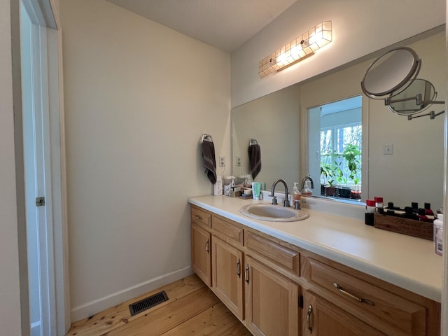 bathroom featuring vanity, visible vents, baseboards, and wood finished floors