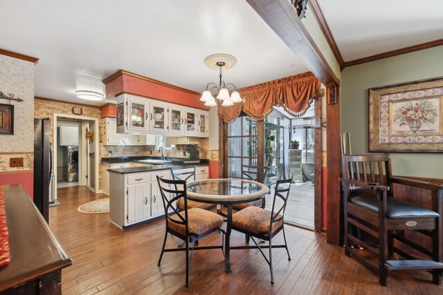 124 Timber Trail Dr, Lebanon, TN 37090 - dining space featuring dark wood-style floors, an inviting chandelier, washer / clothes dryer, and crown molding