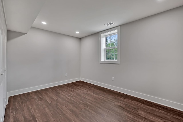 empty room featuring baseboards, dark wood-style floors, visible vents, and recessed lighting