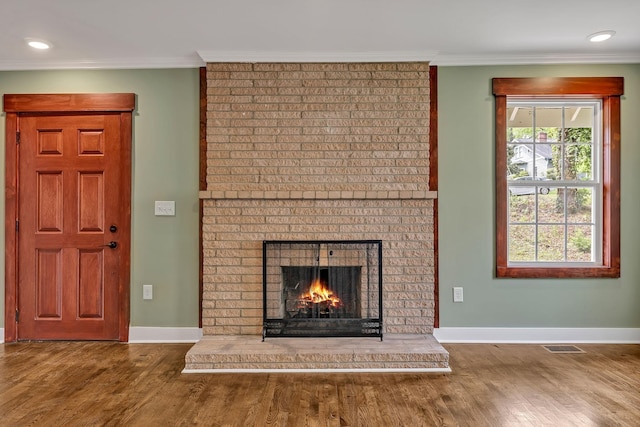 unfurnished living room featuring a brick fireplace, baseboards, and wood finished floors