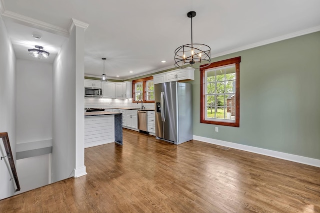 kitchen with a sink, ornamental molding, appliances with stainless steel finishes, and visible vents