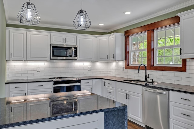 kitchen with white cabinetry, dark stone countertops, appliances with stainless steel finishes, a sink, and hanging light fixtures