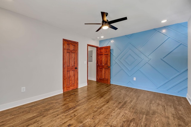 spare room with a decorative wall, baseboards, wood finished floors, and ceiling fan