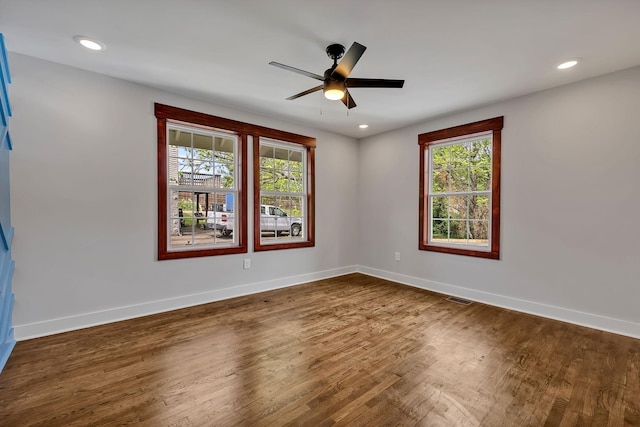 unfurnished room featuring visible vents, dark wood-style flooring, baseboards, and a healthy amount of sunlight