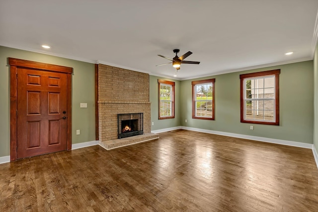unfurnished living room with baseboards, ornamental molding, a fireplace, dark wood-style floors, and ceiling fan