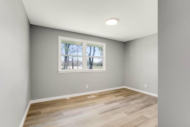 spare room featuring light wood-style flooring, baseboards, and visible vents