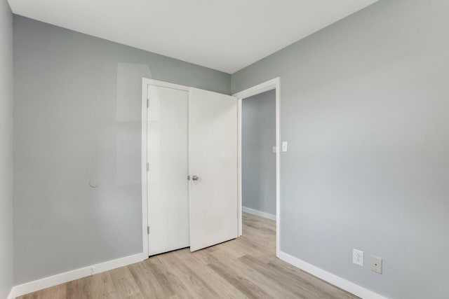 unfurnished bedroom with light wood-style floors, a closet, and baseboards