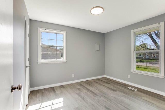 spare room with visible vents, baseboards, and wood finished floors