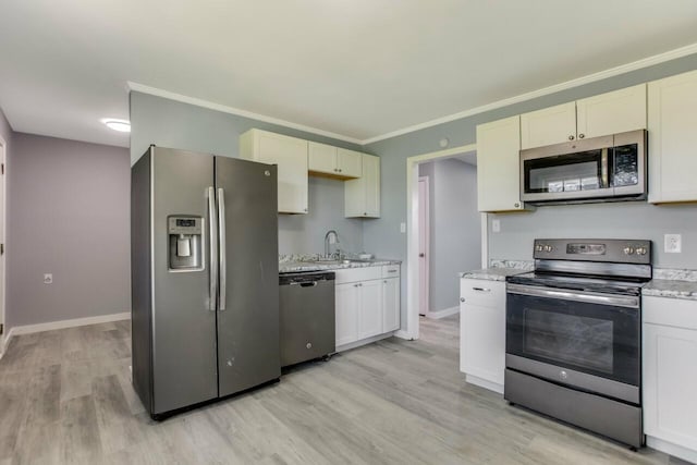 kitchen featuring baseboards, crown molding, appliances with stainless steel finishes, light wood finished floors, and a sink