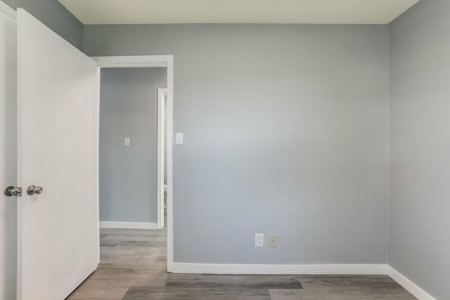 spare room with baseboards and wood finished floors