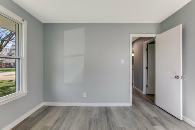 empty room featuring wood finished floors, baseboards, and plenty of natural light