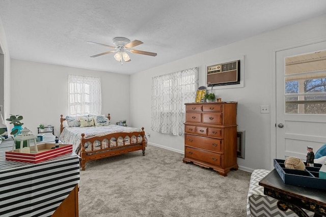 bedroom featuring light carpet, baseboards, a wall unit AC, and a ceiling fan