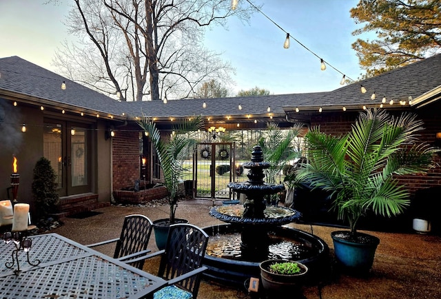 rear view of property featuring a patio area, french doors, and a shingled roof
