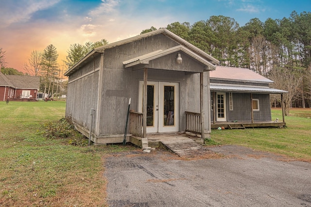 view of front of home with french doors, metal roof, and a lawn