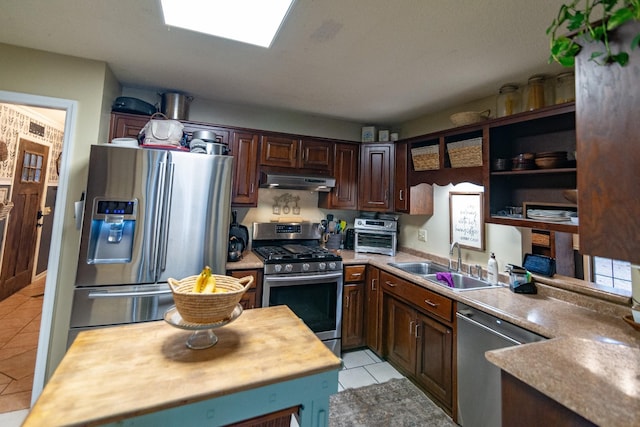 kitchen with a sink, appliances with stainless steel finishes, dark brown cabinetry, under cabinet range hood, and light tile patterned flooring