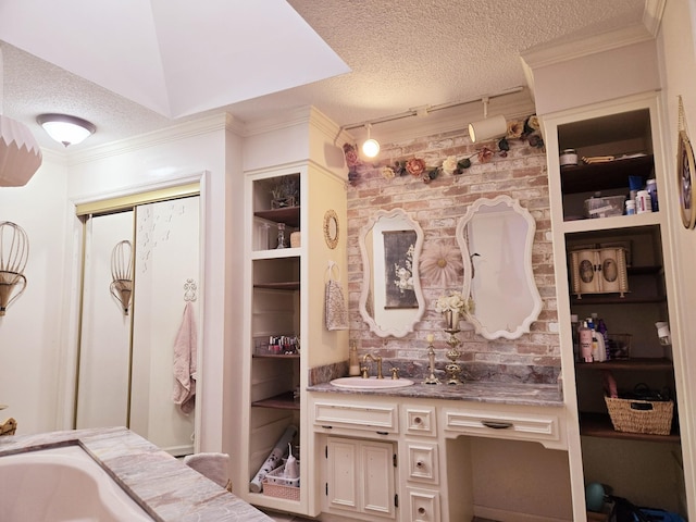 full bath featuring a textured ceiling, built in features, vanity, and ornamental molding