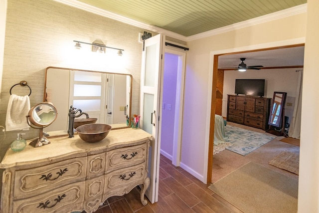 bathroom with ceiling fan, vanity, ornamental molding, wood finished floors, and baseboards
