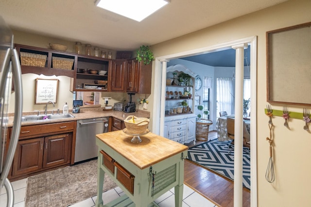 kitchen with butcher block countertops, a sink, open shelves, and appliances with stainless steel finishes