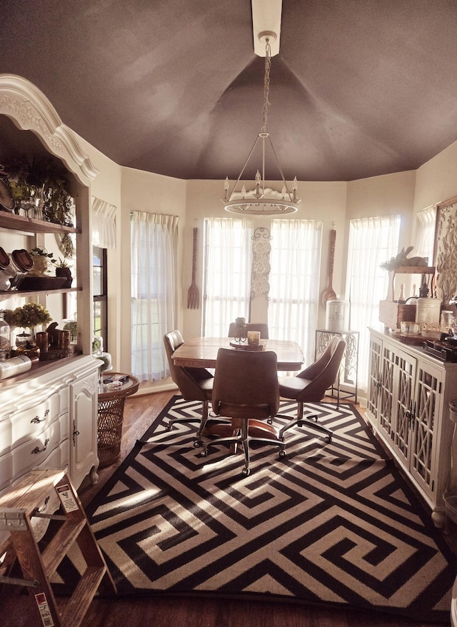 dining area featuring wood finished floors, a notable chandelier, and lofted ceiling
