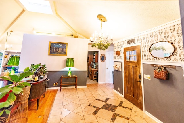 entrance foyer with light tile patterned floors, baseboards, an inviting chandelier, vaulted ceiling, and wallpapered walls