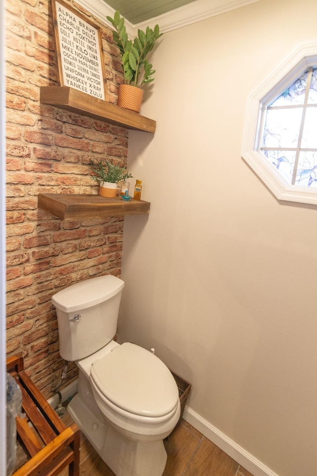 bathroom featuring toilet, crown molding, wood finished floors, and baseboards