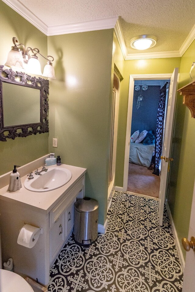 bathroom with baseboards, vanity, a textured ceiling, and ornamental molding