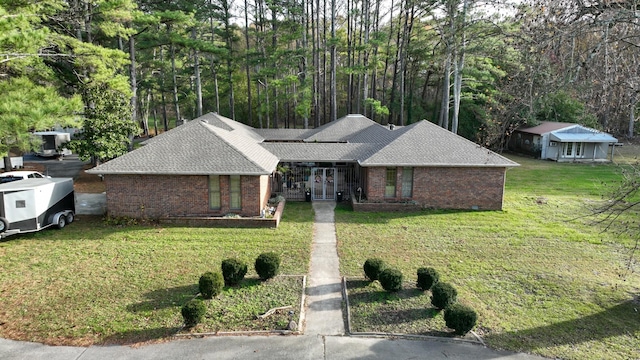 ranch-style home featuring a shingled roof, a front yard, and brick siding