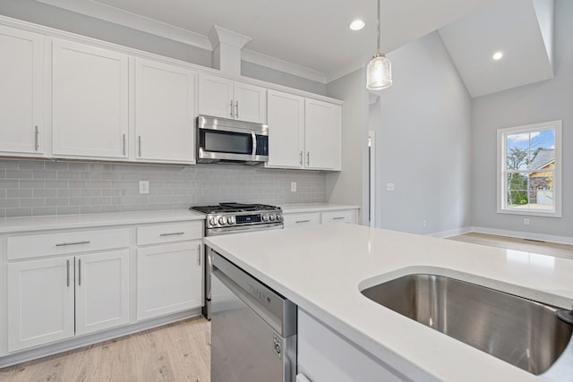 kitchen with light wood-style floors, white cabinetry, appliances with stainless steel finishes, light countertops, and hanging light fixtures