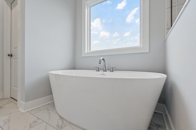 bathroom with a wealth of natural light, marble finish floor, and baseboards