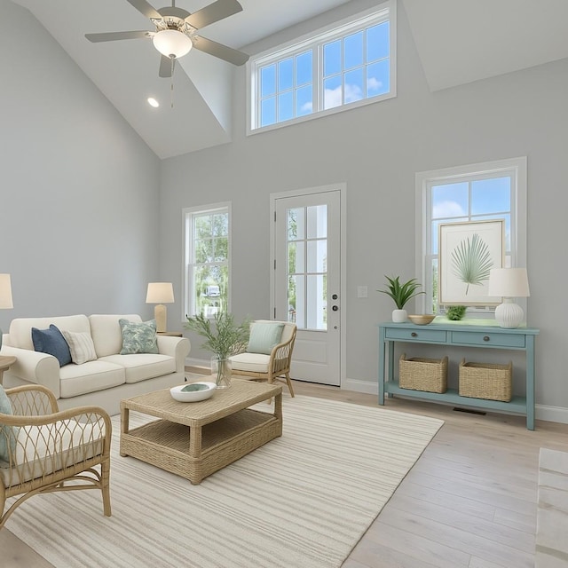 living room featuring baseboards, high vaulted ceiling, light wood-style floors, and a ceiling fan