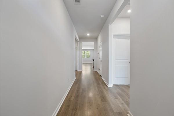 corridor featuring visible vents, baseboards, recessed lighting, and wood finished floors