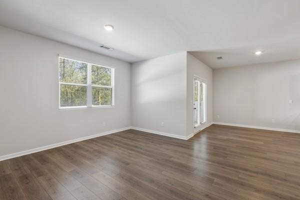 empty room with dark wood-style flooring, baseboards, visible vents, and recessed lighting
