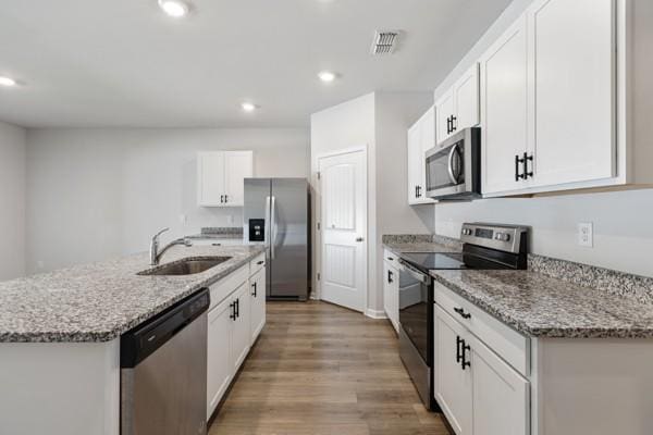 kitchen with white cabinets, visible vents, appliances with stainless steel finishes, a sink, and light wood finished floors