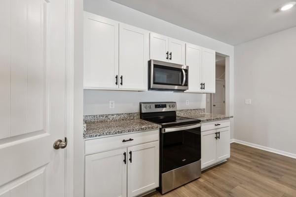 kitchen featuring stainless steel appliances, light wood-type flooring, white cabinets, and baseboards