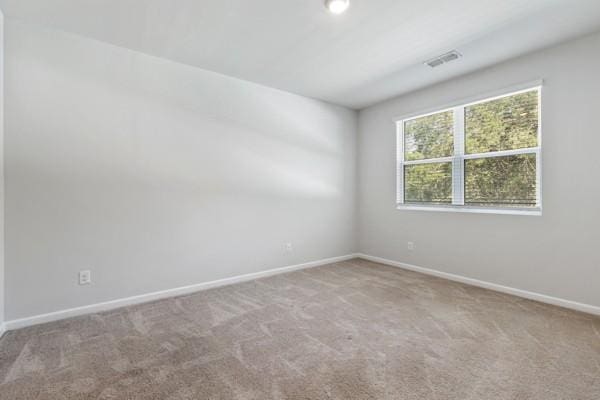 spare room featuring visible vents, baseboards, and carpet