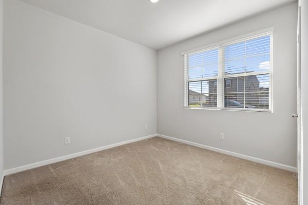 carpeted empty room featuring baseboards