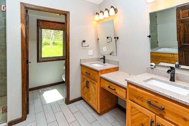 full bath featuring a sink, visible vents, two vanities, and baseboards