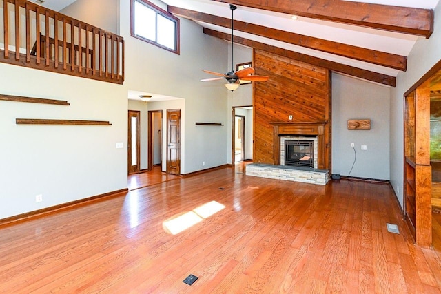 unfurnished living room featuring baseboards, a ceiling fan, wood finished floors, and a glass covered fireplace